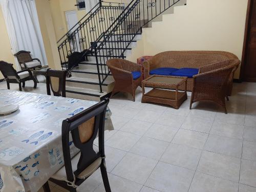 un salon avec des chaises, des tables et un escalier dans l'établissement DINO1, à Trou aux Biches