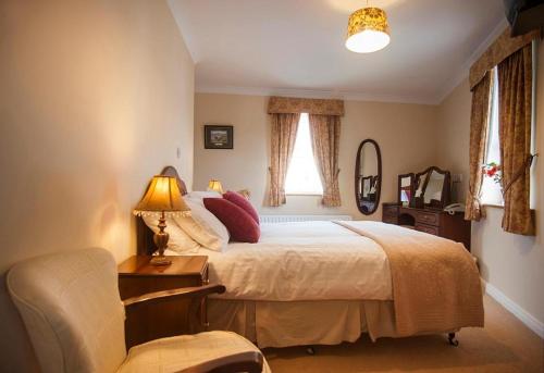 um quarto com uma cama, uma cadeira e um candeeiro em Dun Ri Guesthouse em Clifden