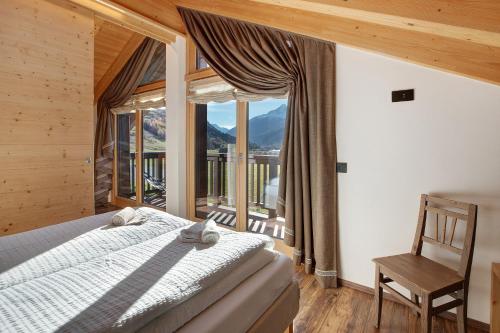 um quarto com uma cama e uma grande janela em Olympic Chalet 13 em Bormio