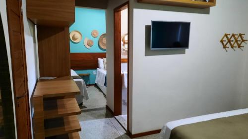 a room with a bed and a tv on a wall at Pousada Carapeba in São Francisco
