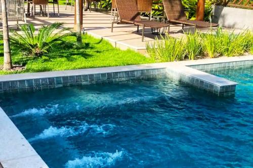 a swimming pool with blue water in a yard at Casa Praia do Forte Bahia Jardim Piscina Churrasco in Praia do Forte