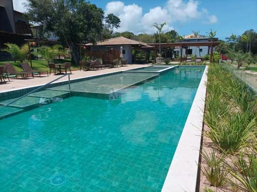 Casa Praia do Forte Bahia Jardim Piscina Churrasco في برايا دو فورتي: مسبح بمياه زرقاء في منتجع
