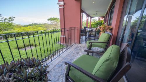 un porche con sillas verdes y una valla en Boungainvillea 7105 Luxury Apartment - Reserva Conchal, en Playa Conchal