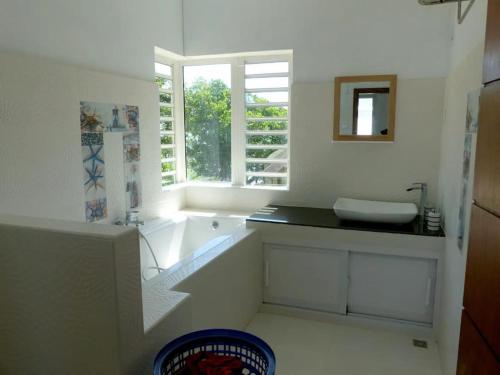 ein Bad mit einer Badewanne, einem Waschbecken und einem Fenster in der Unterkunft Villa la Perle, piscine privée, vue sur le lagon in Mahébourg