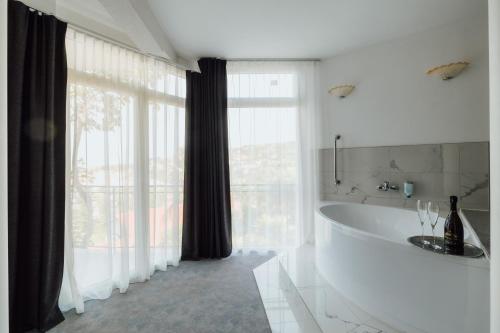 een witte badkamer met een bad en een groot raam bij Villa Bellevue Portoroz-Portorose in Portorož