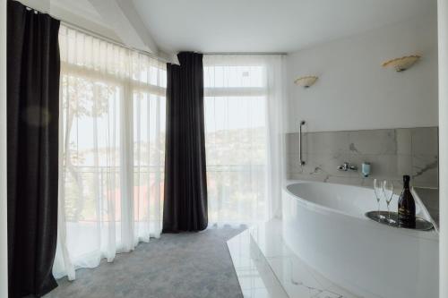 uma casa de banho branca com uma banheira e uma grande janela. em Villa Bellevue Portoroz-Portorose em Portorož