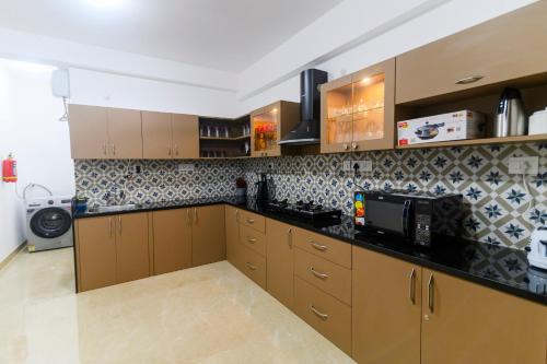 a kitchen with wooden cabinets and a microwave at Lotus & Orchid Villas by Ramnath Homes in Sangolda