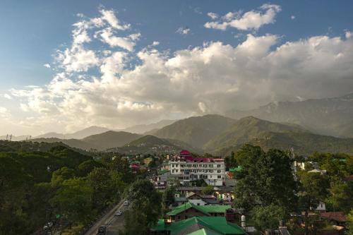 a view of a city with mountains in the background at INFINITEA CENTRIC DHARAMSHALA in Dharamshala