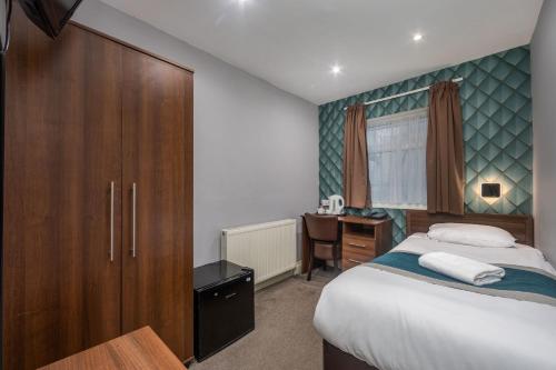 a bedroom with a bed and a desk and a cabinet at King Solomon Hotel- Golders Green in London