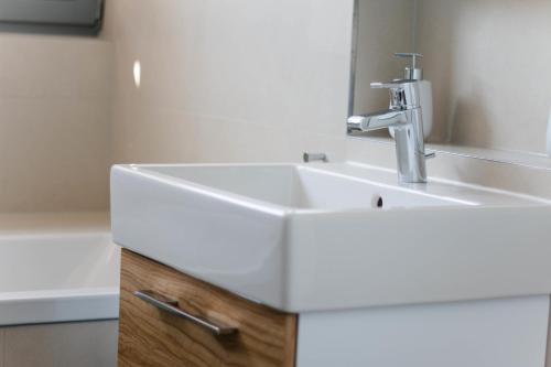ein Badezimmer mit einem weißen Waschbecken und einem Spiegel in der Unterkunft Ostsee - Reetdachhaus Nr 2 "SÜDSTRANDHUS" im Strand Resort in Heiligenhafen