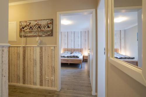 einen Flur mit einem Zimmer mit einem Bett und einem Spiegel in der Unterkunft Solymar Pelzerhaken in Neustadt in Holstein