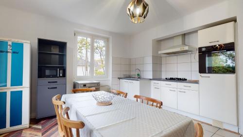une cuisine avec une table blanche, une table et des chaises dans l'établissement Appartement Le Passage - Ostheim, à Ostheim