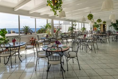 Hotel Ossidiana Stromboli Center في سترومبولي: غرفة طعام مع طاولات وكراسي ونوافذ