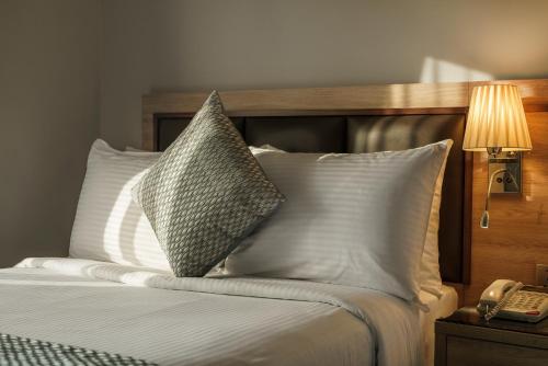 a bedroom with a bed with pillows and a phone at Hotel Holiday International in Sharjah