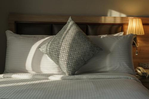 a bed with white pillows and a wooden headboard at Hotel Holiday International in Sharjah