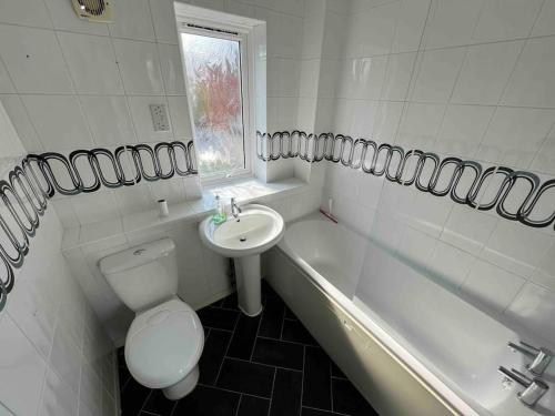 La salle de bains est pourvue de toilettes, d'un lavabo et d'une baignoire. dans l'établissement 3 bedroom house with parking, à Manchester