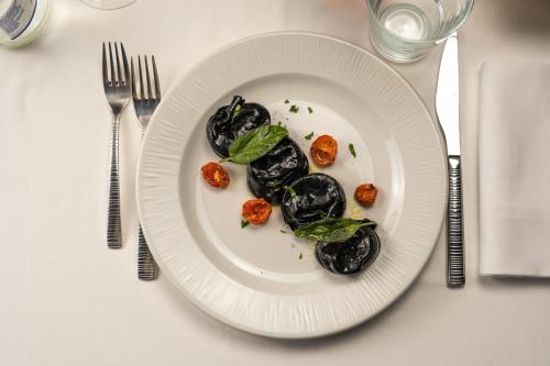 a white plate of food on a table with silverware at Emotional Grand Motel in Fontaneto dʼAgogna
