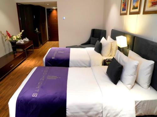 a hotel room with two beds and a chair at Indigo Heights Hotel & Suites in Lahore