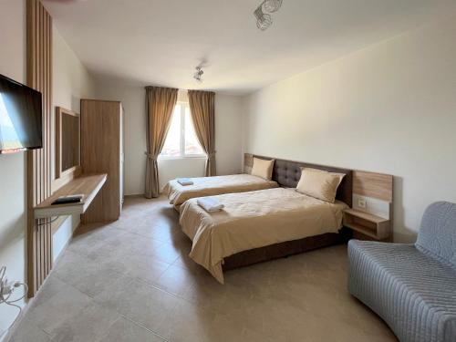 um quarto de hotel com duas camas e um sofá em Guest Houses Kapatovo / Къщи за гости КАПАТОВО 