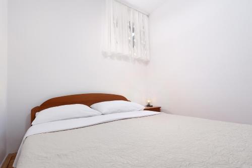a bedroom with a bed with white sheets and a window at Jadranovo Dunja in Jadranovo