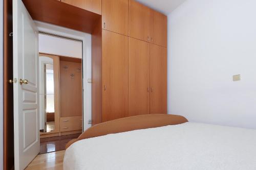 a bedroom with a white bed and wooden cabinets at Jadranovo Dunja in Jadranovo