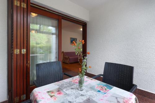 a dining room table with a vase of flowers on it at Jadranovo Dunja in Jadranovo