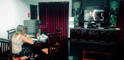 a woman sitting at a table watching a tv at GB25 inn in Trivandrum