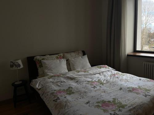 a bedroom with a bed with a floral comforter and a window at Riga RiverPark - One-Bedroom Apartment Near Downtown in Rīga