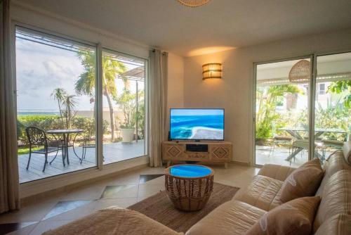 a living room with a couch and a flat screen tv at PASHA - Ocean view in Sainte-Anne