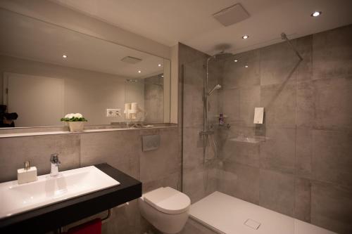 a bathroom with a toilet and a sink and a shower at Landhotel Bartmann in Sendenhorst