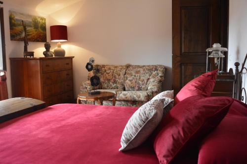 a bedroom with a bed with red sheets and a couch at Borgodoro - Natural Retreat in Magliano Sabina