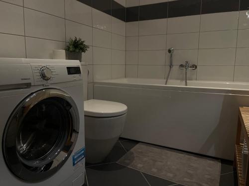 a bathroom with a washing machine and a bath tub at Riga RiverPark - One-Bedroom Apartment Near Downtown in Rīga