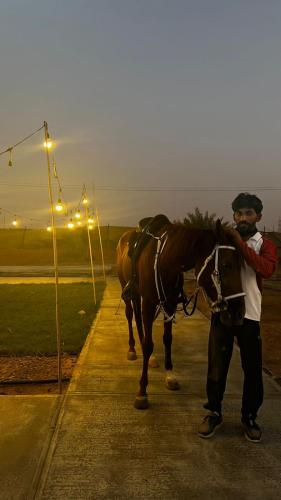 a man standing next to a horse on a sidewalk at The Hidden Lodge in Al Ain