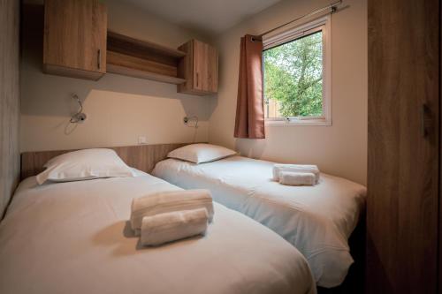 2 camas en una habitación con ventana en Camping de l'Orangerie de Lanniron en Quimper