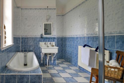 a blue tiled bathroom with a tub and a sink at Finest Retreats - Edwardian Country House - 9 Bed, Sleeping up to 21 in Longtown