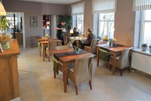 un restaurante con mesas y sillas de madera y gente comiendo en Hotel Alte Landschule en Langballig