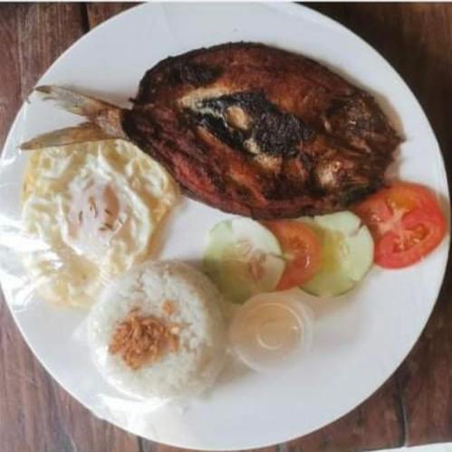 a plate of food with a piece of meat and vegetables at Nine Balconies Island Stay in Boac