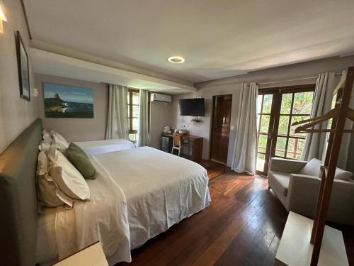 Un dormitorio con una gran cama blanca y una silla. en Pousada Simpatia da Ilha, en Fernando de Noronha