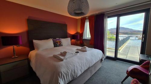 una camera da letto con un grande letto con una grande finestra di Taransay House, Small Hotel a Portree