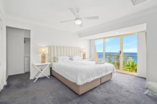 a white bedroom with a large bed and a window at Spacious Home with Ocean Views, Close to Beach in Wamberal