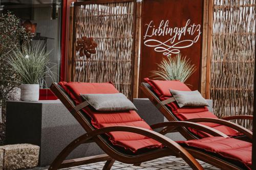 two chairs with red cushions sitting on a patio at PANORAMA Hotel Heimbuchenthal in Heimbuchenthal