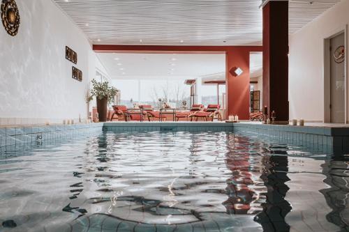 a swimming pool in a hotel with tables and chairs at PANORAMA Hotel Heimbuchenthal in Heimbuchenthal