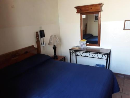 a bedroom with a blue bed and a mirror at Hotel el Carmen, Morelia in Morelia