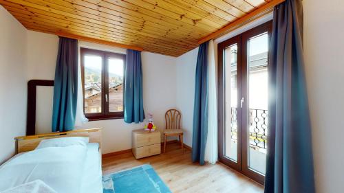 een slaapkamer met blauwe gordijnen, een bed en een raam bij Superb family apartment in centre of the village of Vercorin in Vercorin