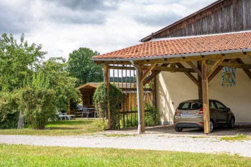 a car parked under a wooden pavilion next to a house at Ferienwohnung Haus Inge in Moosbach