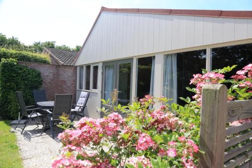 a patio with a table and chairs and flowers at Rekerlanden 98 in Schoorldam