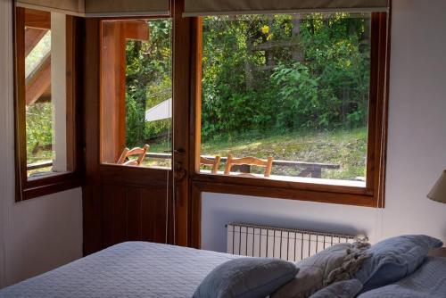 拉安戈斯圖拉鎮的住宿－Casa del Sur Villa La Angostura，一间卧室设有一张床和一个美景窗户。