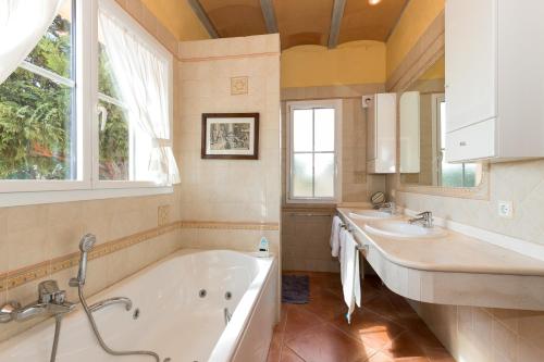 La salle de bains est pourvue de 2 lavabos, d'une baignoire et d'une fenêtre. dans l'établissement Villa Estrellita Sant Lluis, à Sant Lluis
