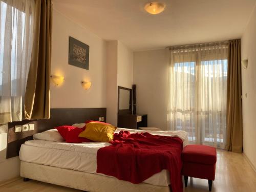 a bedroom with a bed with a red blanket on it at Banderitsa Apartments with kitchen & BBQ in Bansko