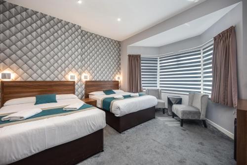 a hotel room with two beds and a chair at King Solomon Hotel- Golders Green in London
